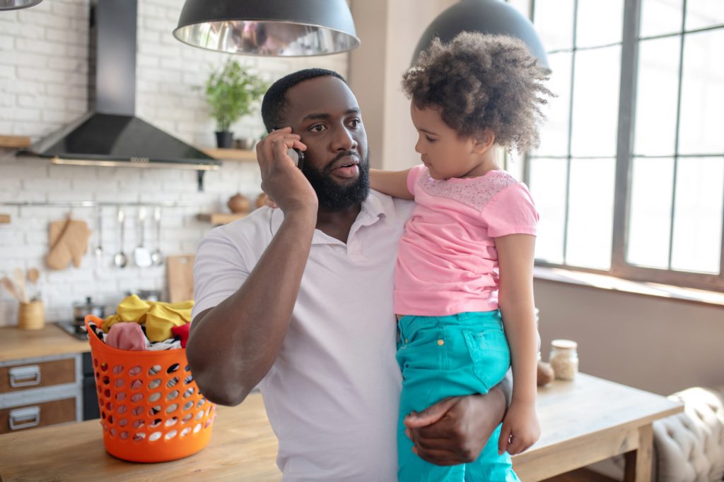 Father Taking Phone Call While Holding Daughter